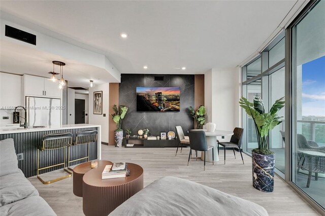 living room featuring sink, floor to ceiling windows, and light hardwood / wood-style floors