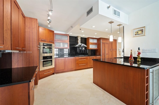 kitchen featuring beverage cooler, tasteful backsplash, stainless steel double oven, wall chimney range hood, and decorative light fixtures