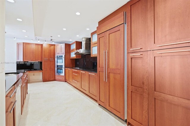 10175 Collins Ave Unit 1003, Bal Harbour, FL 33154 - kitchen with wall chimney range hood, dark countertops, paneled built in fridge, recessed lighting, and brown cabinetry