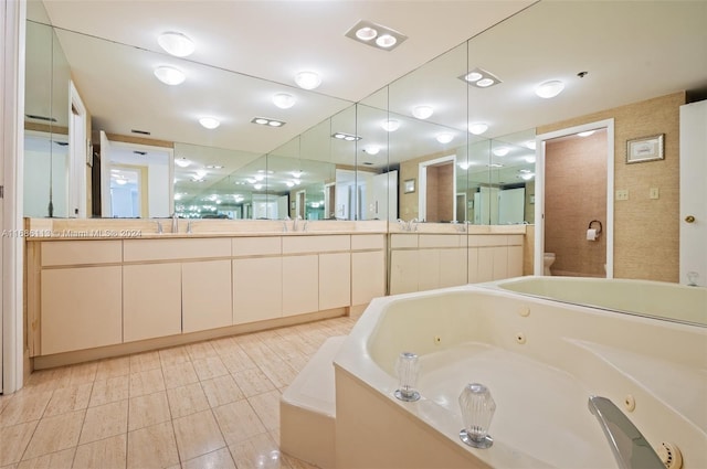 bathroom featuring tile patterned flooring, a washtub, vanity, and toilet