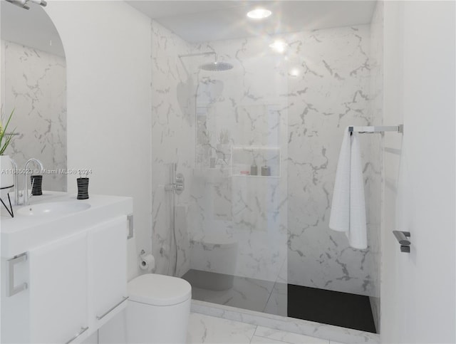 bathroom featuring toilet, vanity, and a tile shower