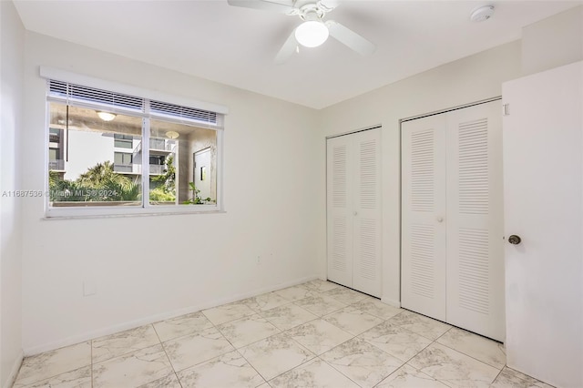 unfurnished bedroom with multiple closets and ceiling fan