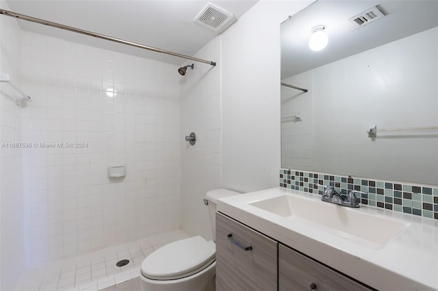 bathroom with tiled shower, vanity, toilet, and backsplash