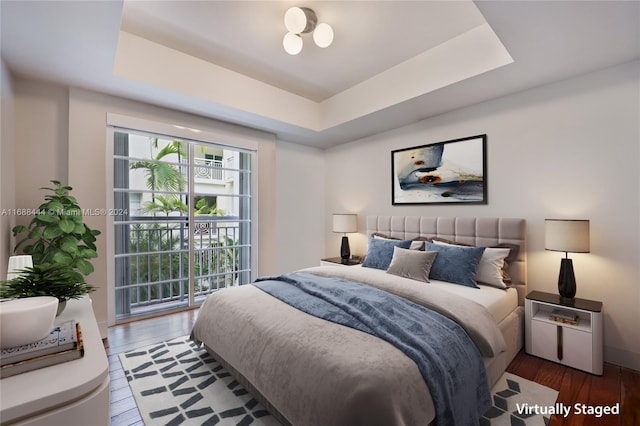 bedroom with a tray ceiling and wood-type flooring