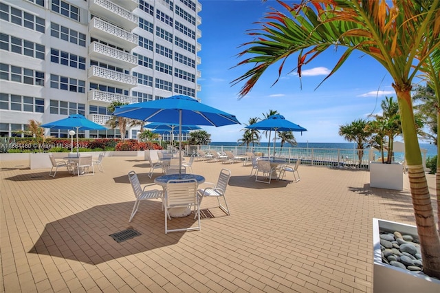 view of property's community with a view of the beach, a patio, and a water view