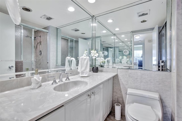 bathroom with walk in shower, vanity, toilet, and tile walls