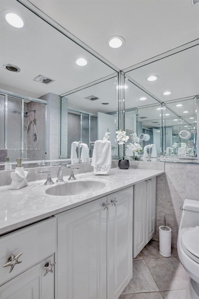 bathroom with an enclosed shower, vanity, tile patterned floors, and toilet