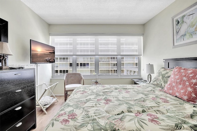 bedroom with a textured ceiling and light hardwood / wood-style floors