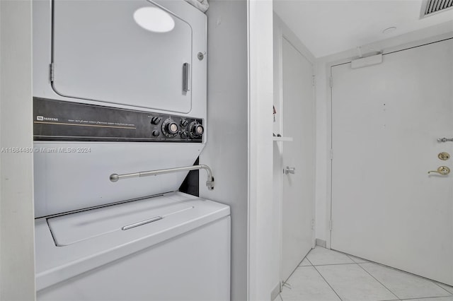 laundry room featuring stacked washing maching and dryer and light tile patterned flooring