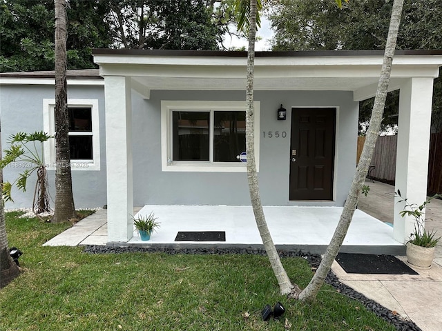 view of exterior entry featuring a yard and stucco siding