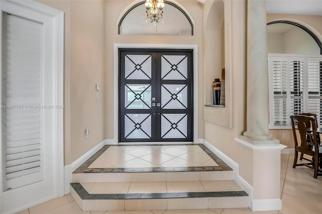 tiled foyer featuring ornate columns, french doors, and an inviting chandelier