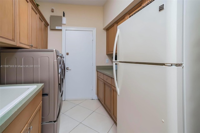 clothes washing area featuring cabinets, light tile patterned floors, and washer / clothes dryer