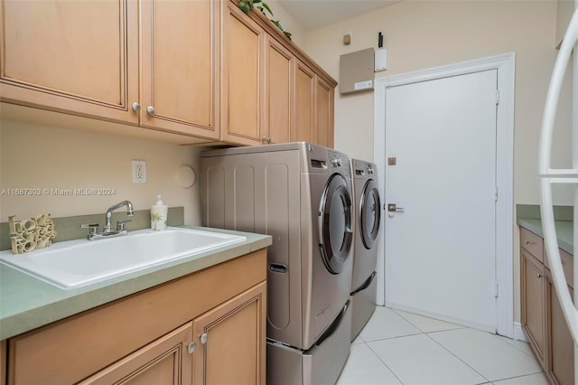 laundry area with cabinets, light tile patterned floors, washer and clothes dryer, and sink