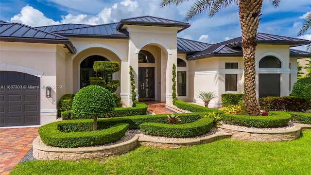 mediterranean / spanish home featuring a garage and a front lawn