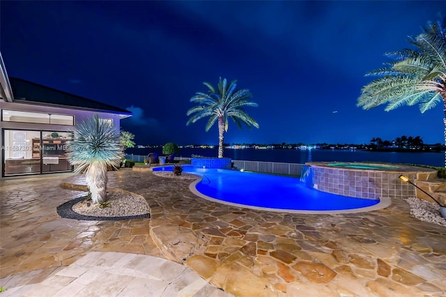 pool at twilight featuring an in ground hot tub, pool water feature, a water view, and a patio area