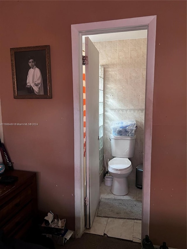 bathroom with tile patterned flooring, tile walls, and toilet