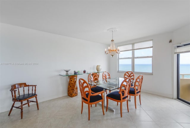 tiled dining room featuring a chandelier and a water view