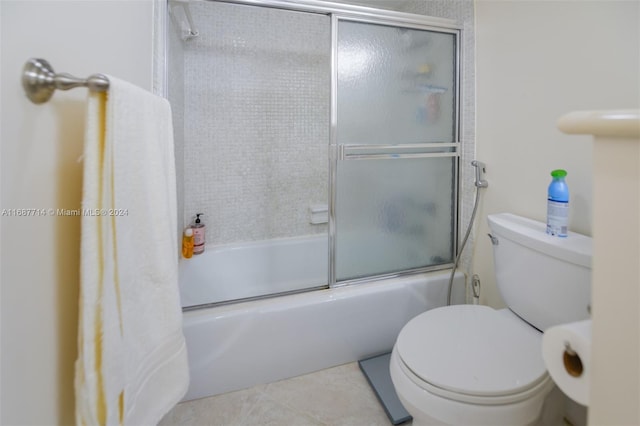 bathroom with bath / shower combo with glass door, tile patterned flooring, and toilet