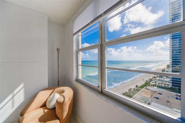 interior space with a healthy amount of sunlight, a beach view, and a water view