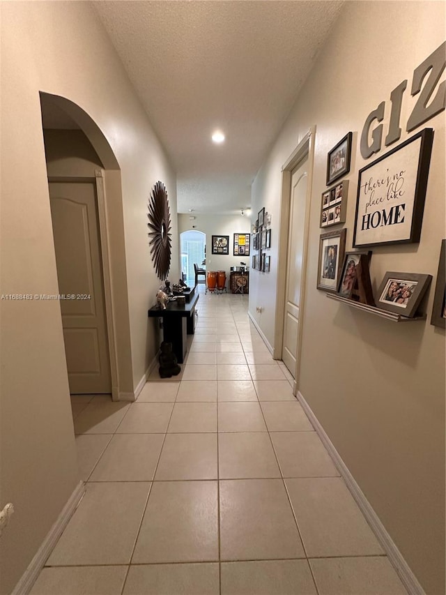 hall with a textured ceiling and light tile patterned floors