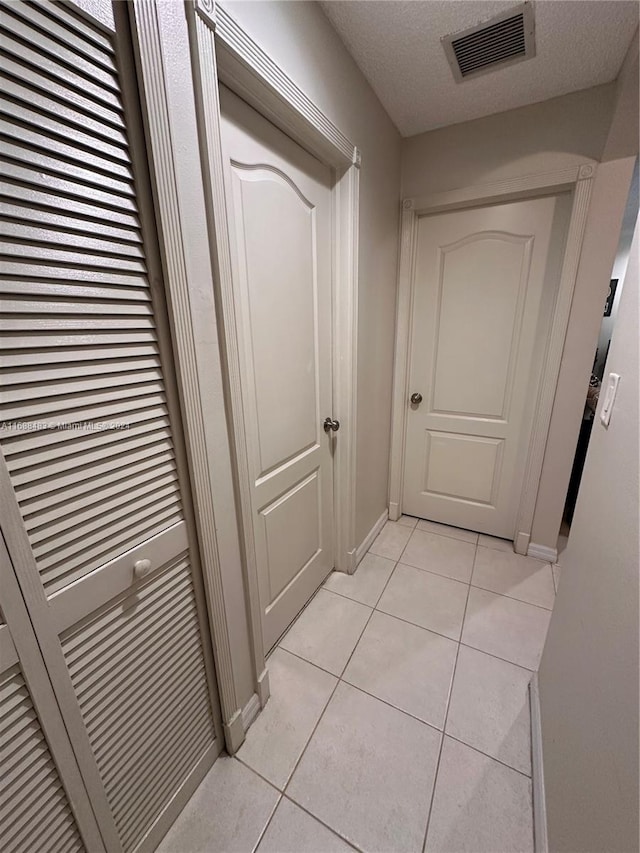 corridor with a textured ceiling and light tile patterned floors