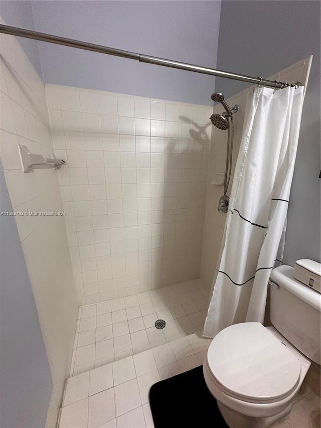 bathroom with toilet, curtained shower, and tile patterned floors