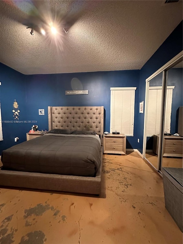 bedroom with concrete floors, a textured ceiling, and a closet