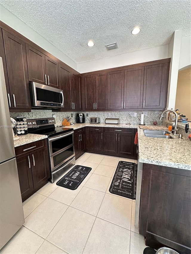 kitchen featuring a textured ceiling, appliances with stainless steel finishes, sink, and tasteful backsplash