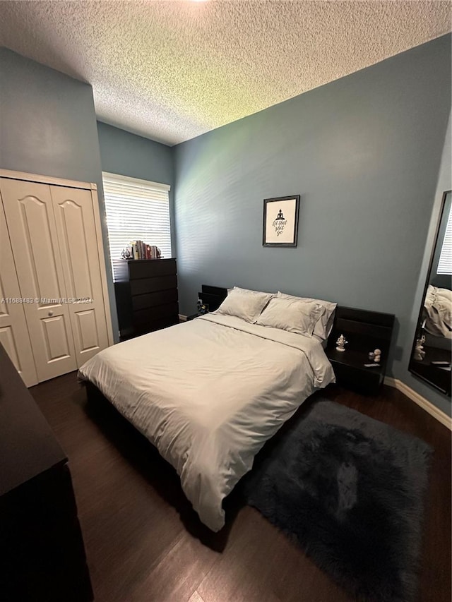 bedroom with a closet, a textured ceiling, and dark hardwood / wood-style floors