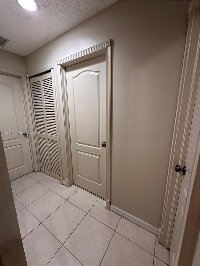 hallway featuring a textured ceiling and light tile patterned floors