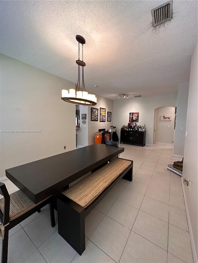 dining area with a textured ceiling and light tile patterned floors