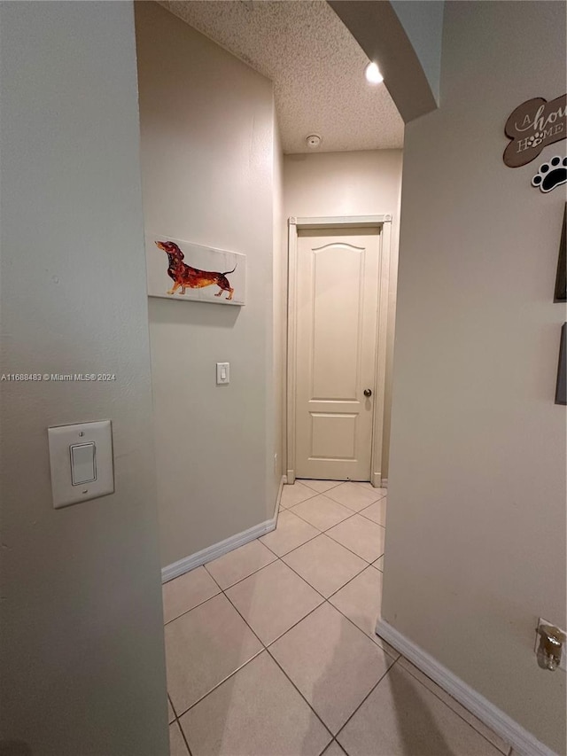 hallway featuring a textured ceiling and light tile patterned floors