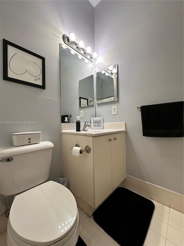 bathroom with toilet, vanity, and tile patterned floors