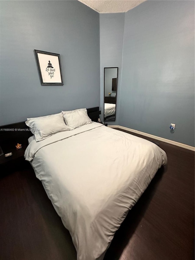 bedroom featuring a textured ceiling and dark hardwood / wood-style floors