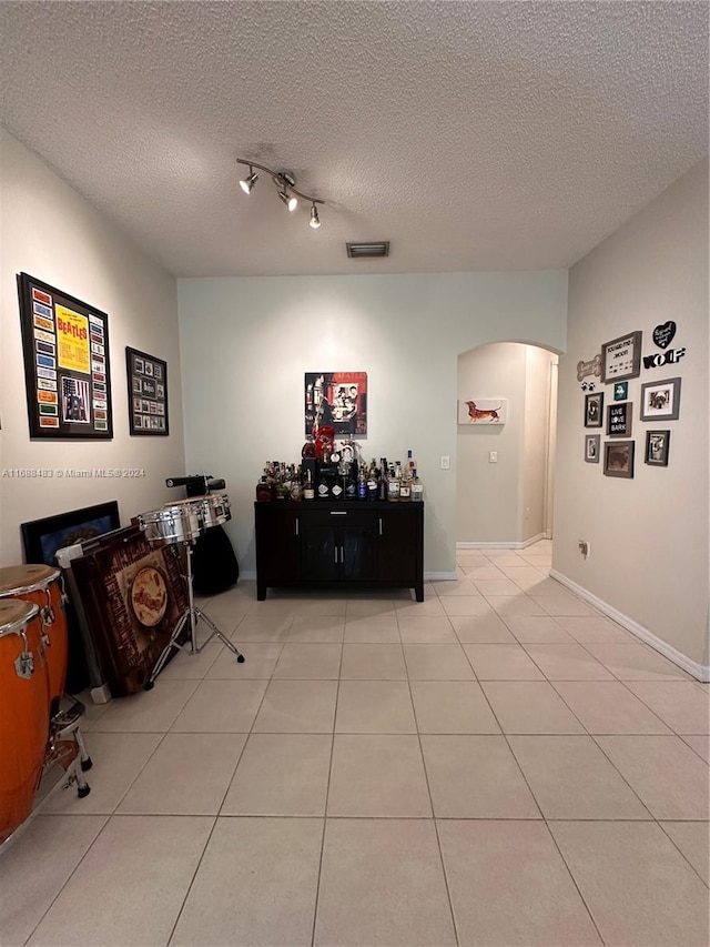 interior space with a textured ceiling and light tile patterned floors