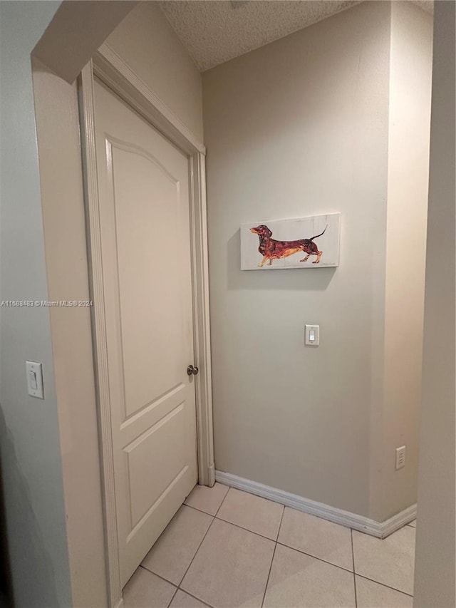 hall featuring a textured ceiling and light tile patterned floors