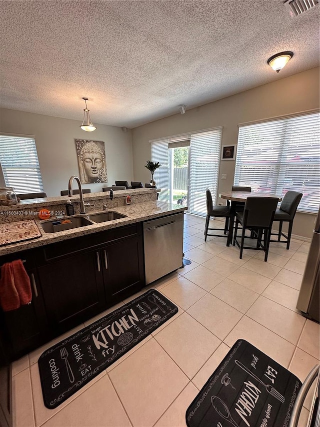 kitchen with dishwasher, a textured ceiling, light tile patterned floors, sink, and pendant lighting