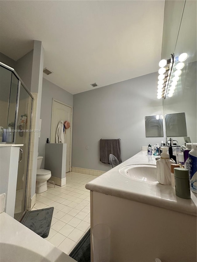 bathroom with toilet, vanity, tile patterned floors, and walk in shower