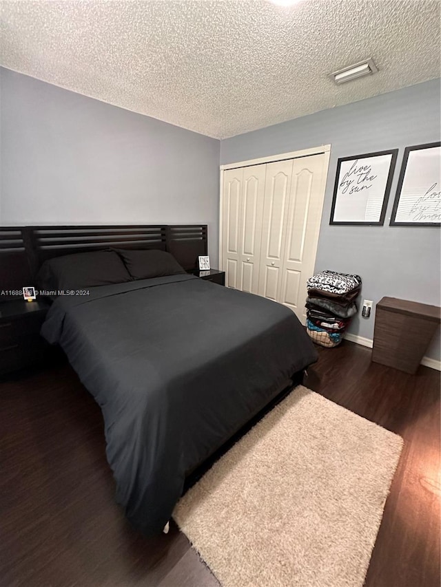 bedroom featuring dark wood-type flooring, a textured ceiling, and a closet