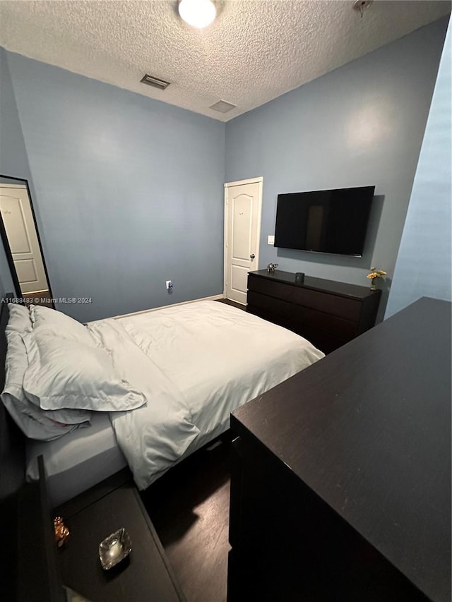 bedroom with hardwood / wood-style flooring and a textured ceiling