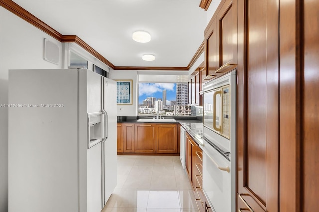 kitchen with sink, white appliances, crown molding, and light tile patterned floors