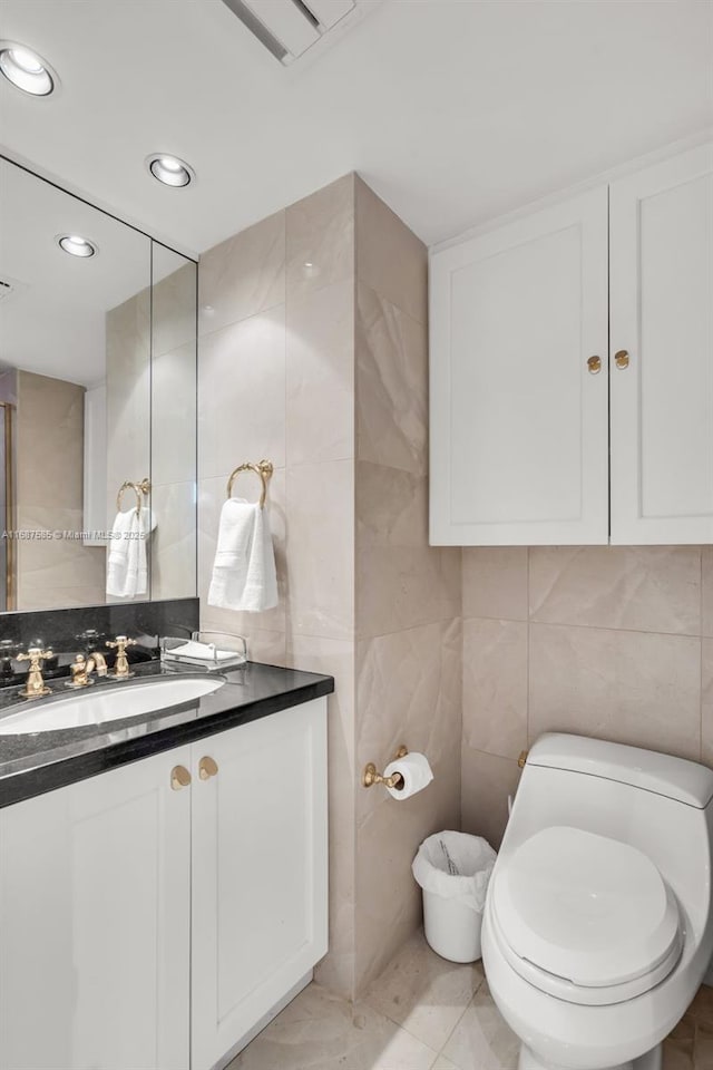 bathroom with tile patterned floors, vanity, toilet, and tile walls