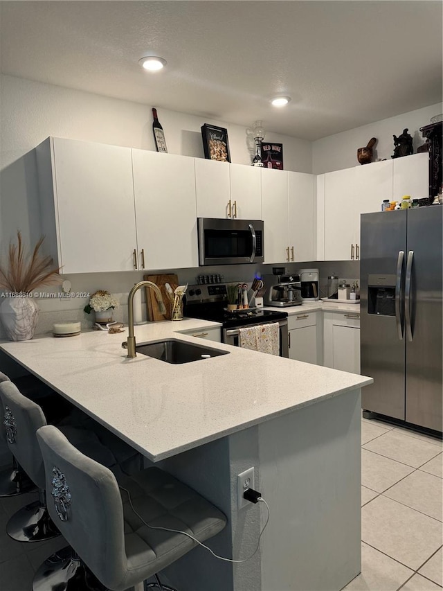 kitchen with white cabinetry, kitchen peninsula, appliances with stainless steel finishes, and sink