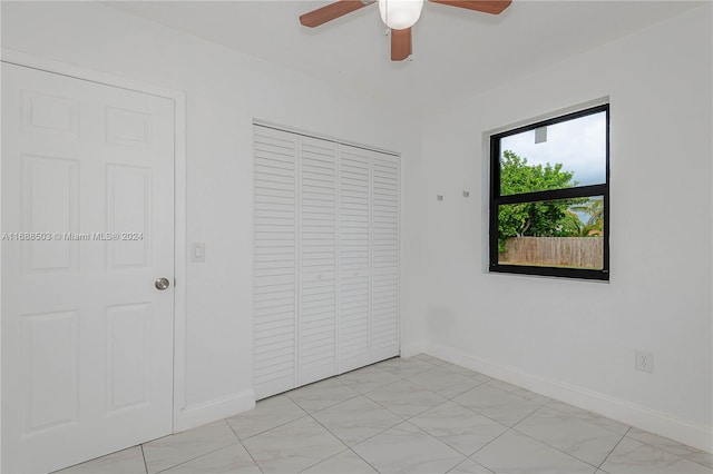 unfurnished bedroom with ceiling fan and a closet