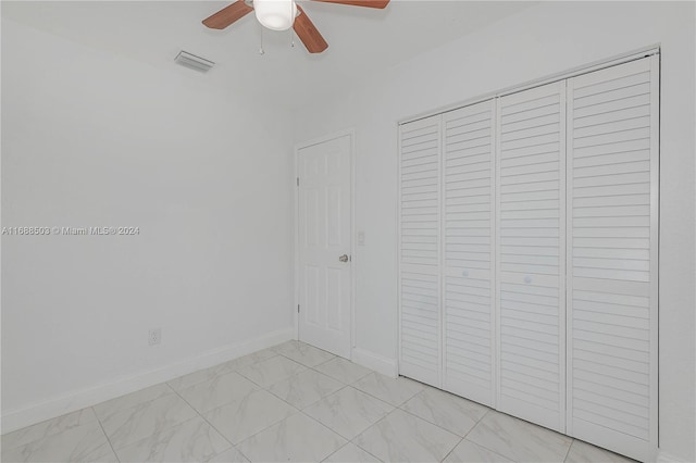 unfurnished bedroom with ceiling fan and a closet