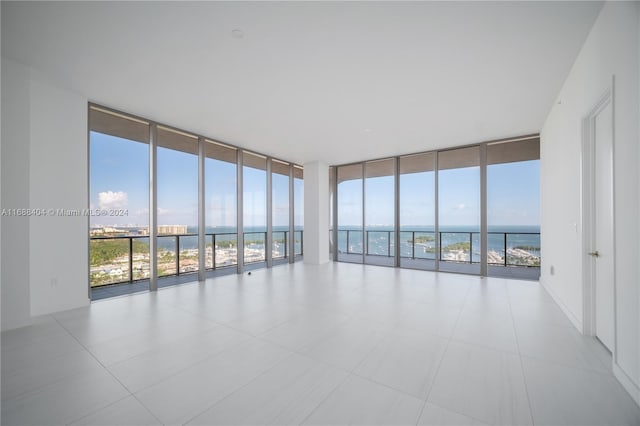 unfurnished room featuring light tile patterned floors, a water view, and floor to ceiling windows