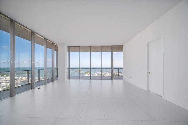 spare room featuring expansive windows, plenty of natural light, and a water view