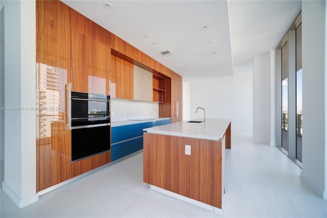 kitchen with electric stovetop, light tile patterned flooring, decorative backsplash, and a center island with sink