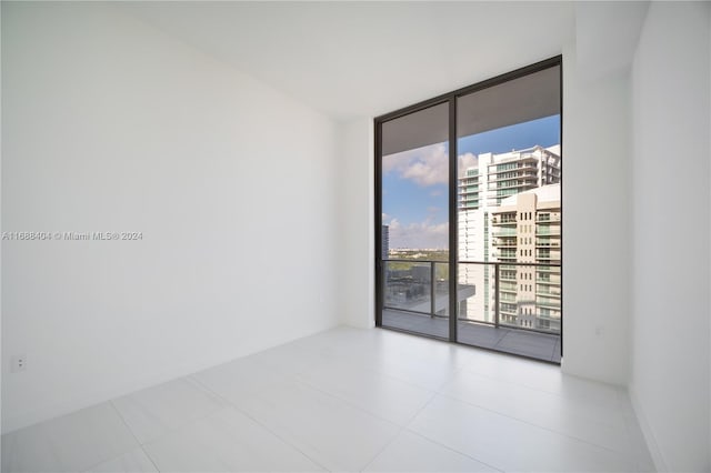 empty room featuring a wall of windows and light tile patterned floors