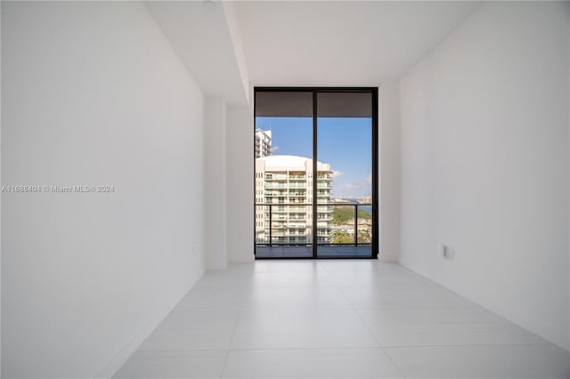 unfurnished room featuring a wall of windows and light tile patterned floors